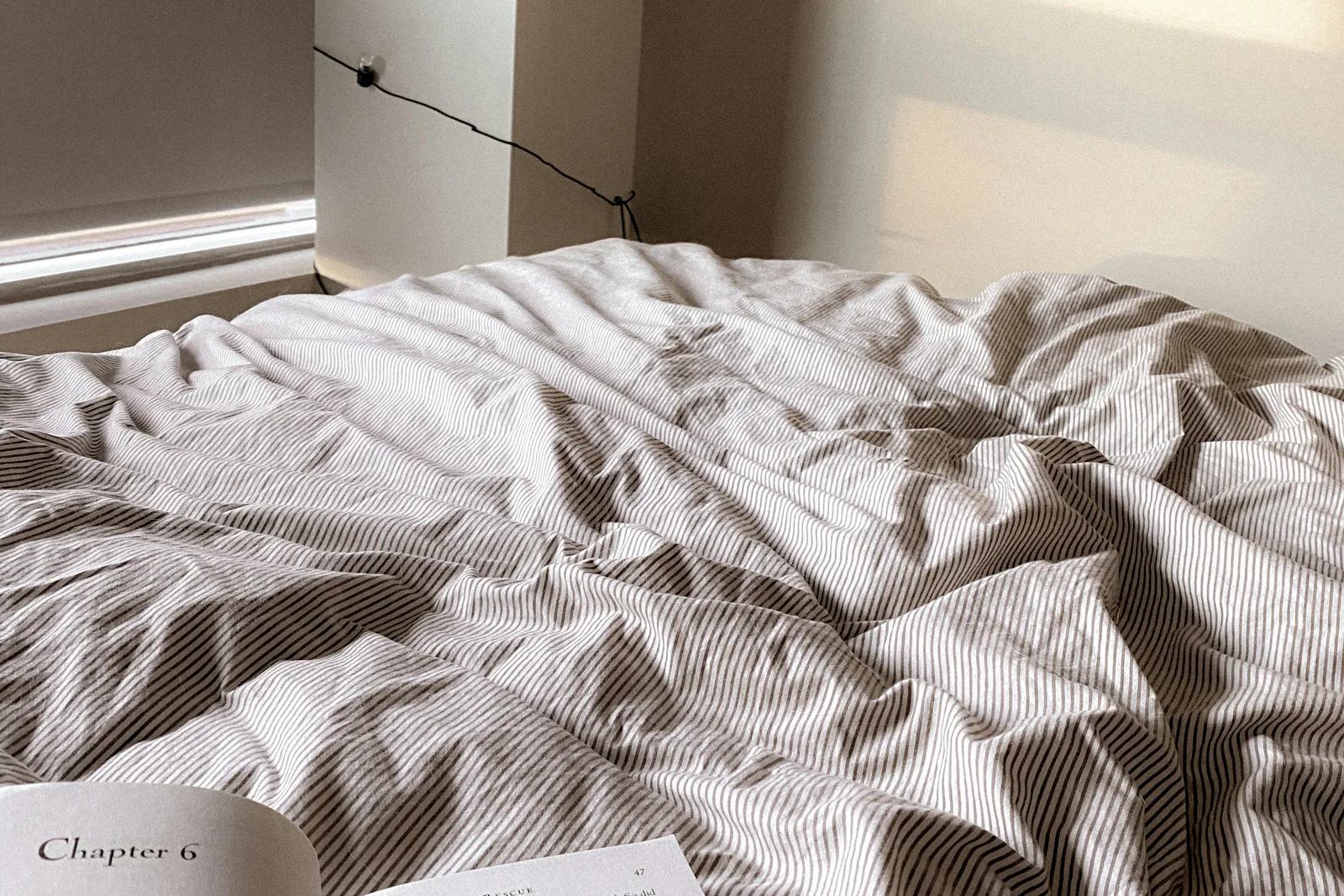 Open book resting on a neatly prepared bed